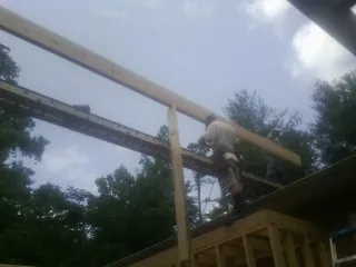 Carpenter setting a ridge beam over a new addition frame — Ice Dam Removal by Roofing Brothers in Block Island