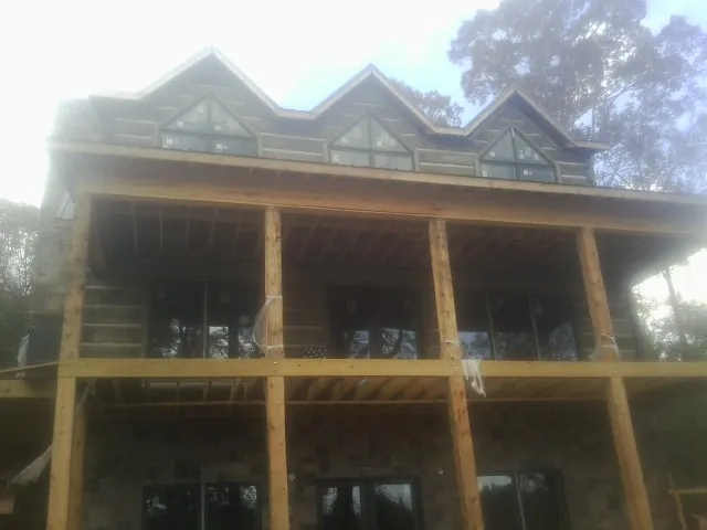Dormers and porch framing on a large log home under construction — Roof Coating work by our crew in Block Island