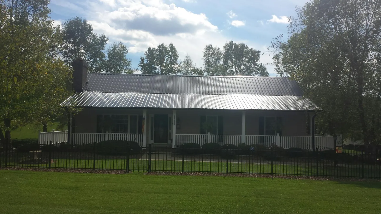 Gray metal roof on a brick ranch with a full width front porch — Gutter Guard Installation work by our crew in Block Island