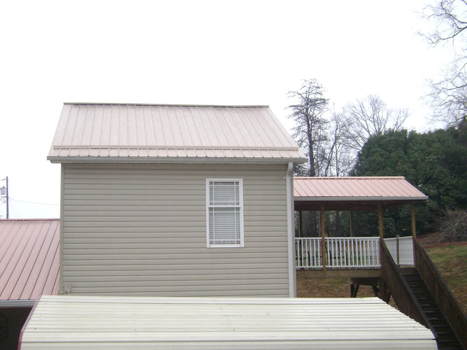 Tan metal roofs on a two story addition and attached porch, from a Roof Replacement job in Block Island