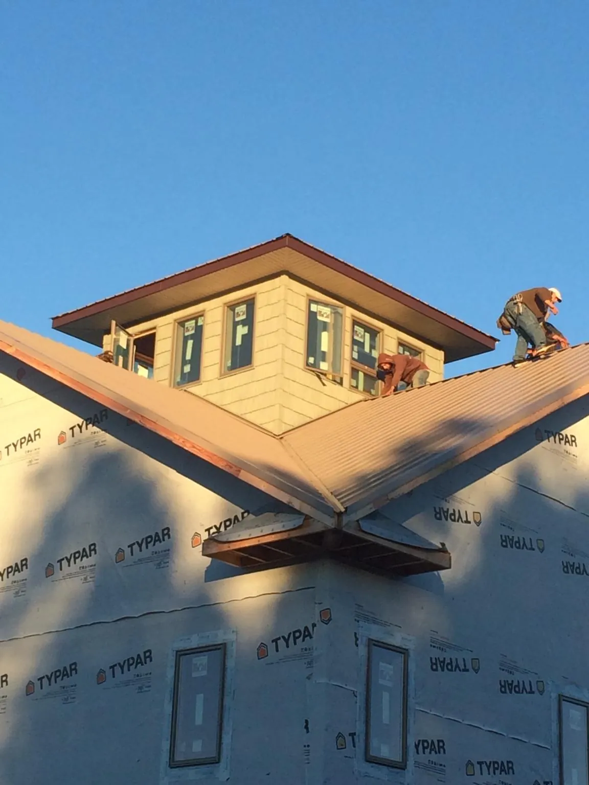 Roofers working around a rooftop cupola on a new metal roof at sunset — Roof Waterproofing in Block Island by Roofing Brothers